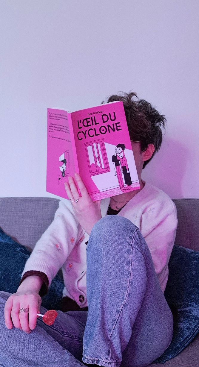 photo de moi assise en train de lire le livre avec une sucette en forme de coeur dans la main