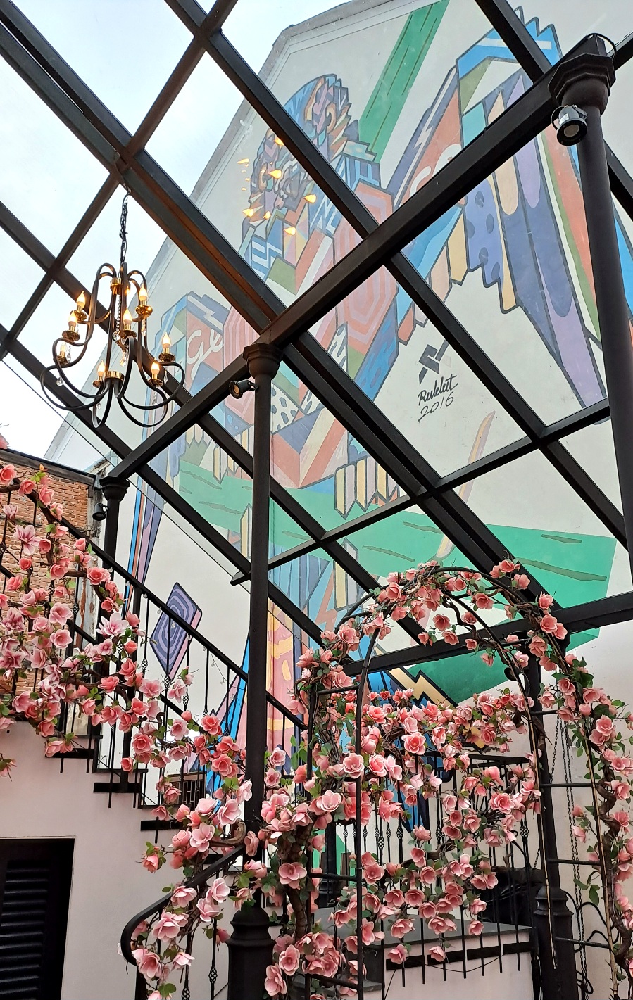 Photo de la ville de Phuket avec un graffiti coloré sur la façade d'un bâtiment et des fausses fleurs roses en premier plan